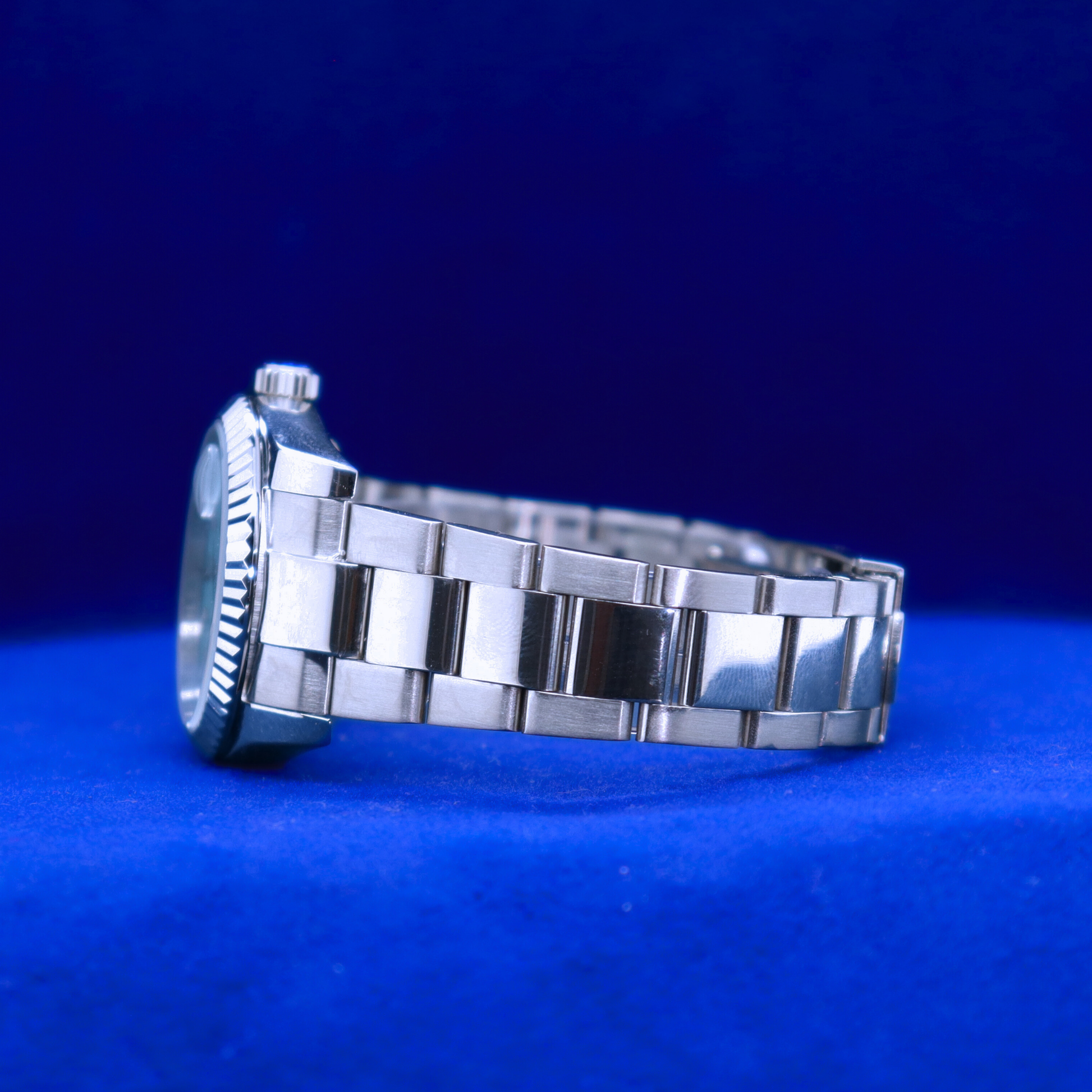 Left side view of half iced out custom sleek blue dial watch featuring metallic accents and minimalist styling