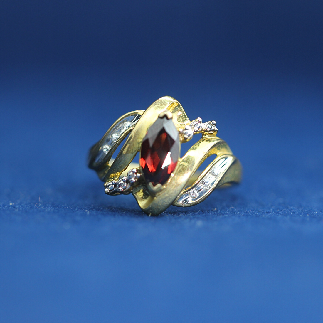 Front view of preowned garnet gold ring crafted in 14K silver with moissanite diamonds – luxury vintage style that pairs with half iced out custom jewelry