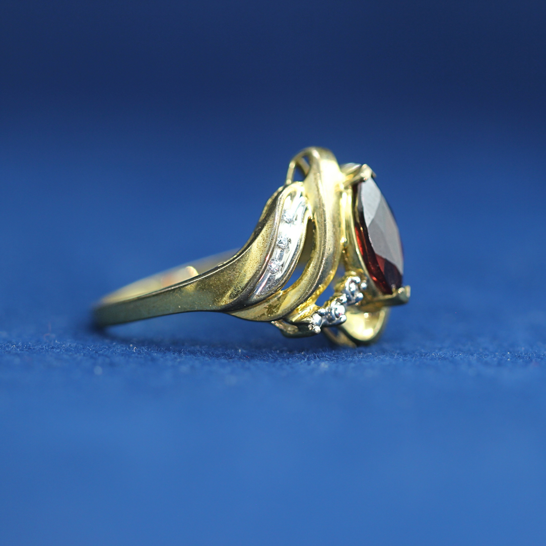Front view of preowned garnet gold ring crafted in 14K silver with moissanite diamonds – luxury vintage style that pairs with half iced out custom jewelry